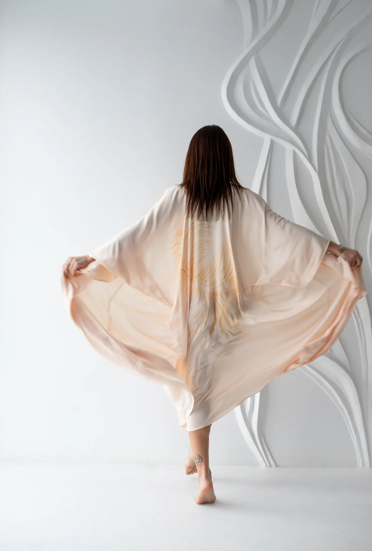 Alena Angel Art — hand-painted silk piece worn against a sculpted white wall
